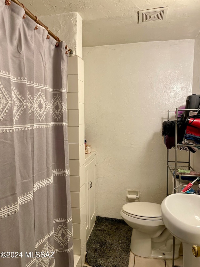 bathroom featuring a shower with curtain, toilet, and sink