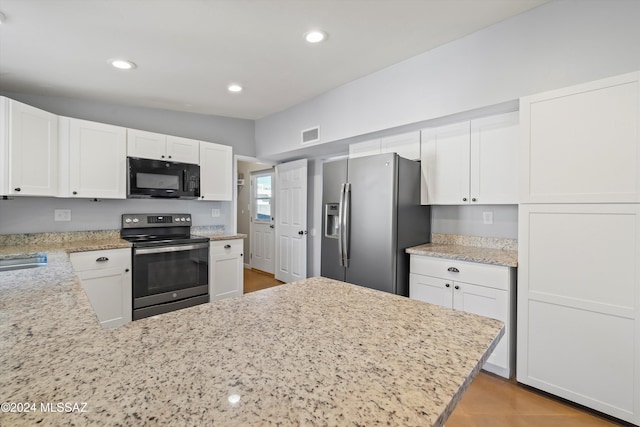 kitchen with white cabinets, appliances with stainless steel finishes, and lofted ceiling