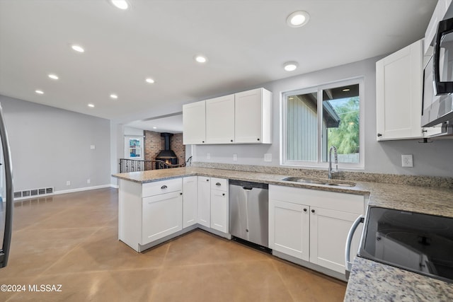 kitchen featuring kitchen peninsula, appliances with stainless steel finishes, light stone countertops, sink, and white cabinets