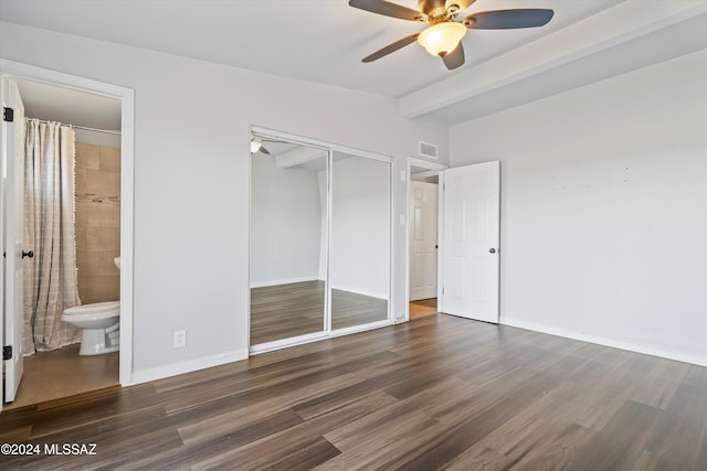 unfurnished bedroom with ensuite bathroom, a closet, dark wood-type flooring, and ceiling fan