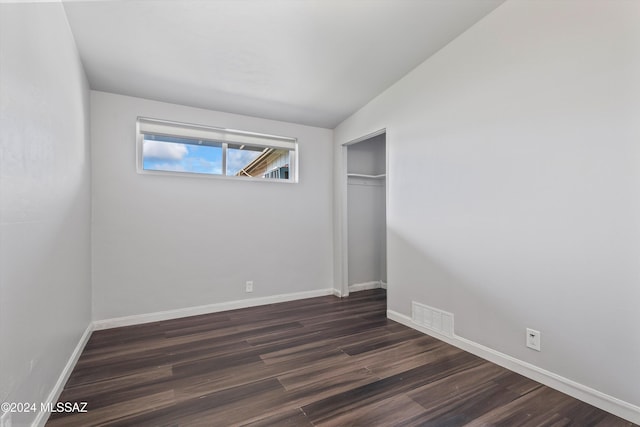 unfurnished bedroom with a closet, dark wood-type flooring, and lofted ceiling