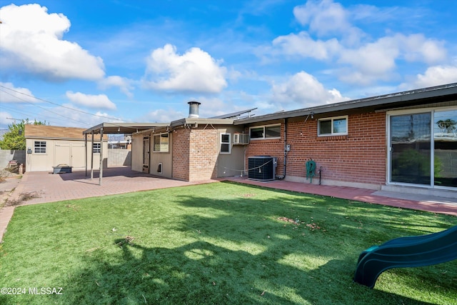 back of property with a lawn, a storage unit, central air condition unit, and a patio