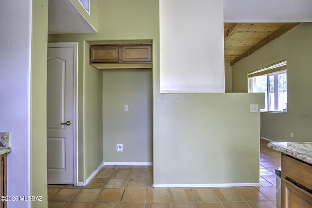 kitchen featuring light tile patterned floors, wooden ceiling, and light stone counters