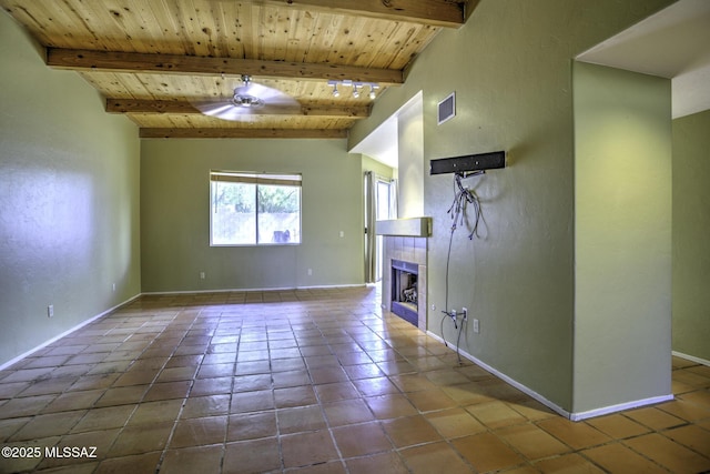 unfurnished living room with a tile fireplace, beamed ceiling, tile patterned flooring, ceiling fan, and wooden ceiling