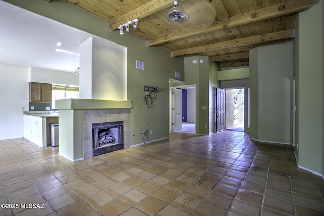 unfurnished living room featuring beam ceiling, wood ceiling, a tile fireplace, and a healthy amount of sunlight