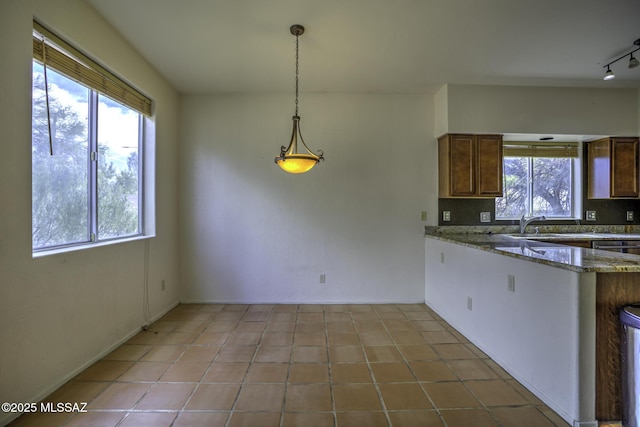 kitchen featuring light tile patterned flooring, rail lighting, light stone counters, and decorative light fixtures