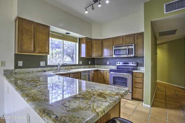 kitchen with light stone countertops, appliances with stainless steel finishes, sink, and kitchen peninsula