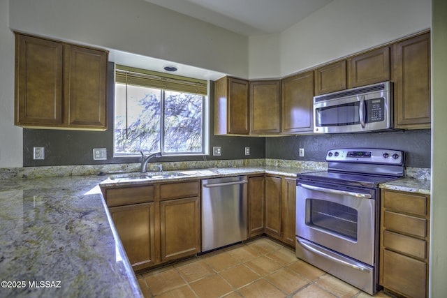 kitchen with light tile patterned flooring, appliances with stainless steel finishes, light stone countertops, and sink