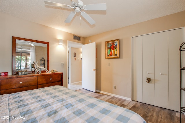 bedroom with a textured ceiling, ceiling fan, light hardwood / wood-style flooring, and a closet