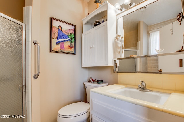 bathroom with vanity, toilet, and a shower with door