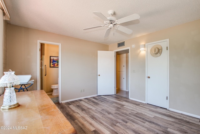 bedroom with ceiling fan, wood-type flooring, a textured ceiling, and connected bathroom