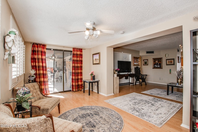 living room featuring ceiling fan, wood-type flooring, and a textured ceiling