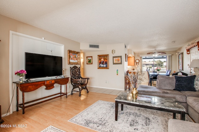 living room with ceiling fan, a textured ceiling, and light wood-type flooring