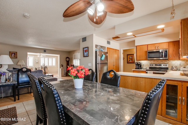 dining space with ceiling fan, light tile patterned flooring, and a textured ceiling