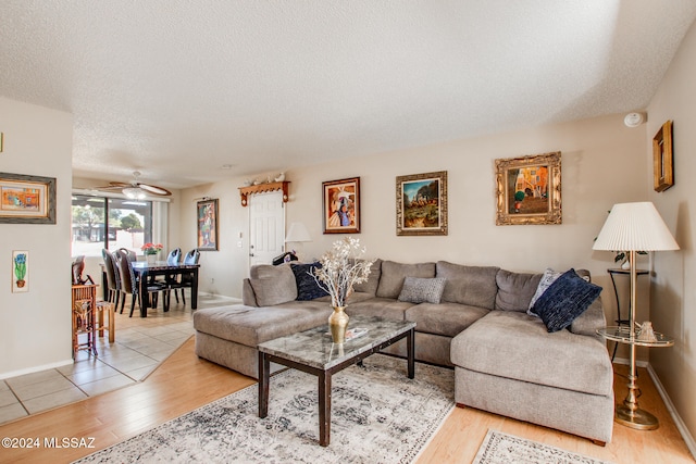 living room with a textured ceiling, light hardwood / wood-style flooring, and ceiling fan