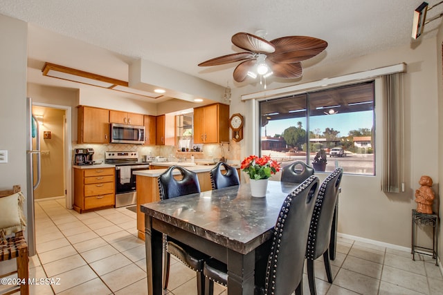 dining area featuring ceiling fan, light tile patterned floors, and a textured ceiling