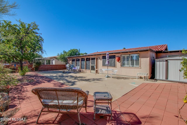 rear view of house with a storage unit and a patio area