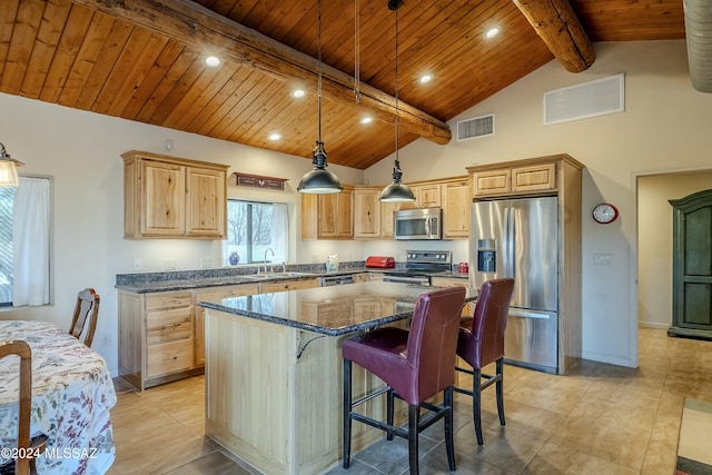 kitchen with beam ceiling, a center island, dark stone counters, pendant lighting, and appliances with stainless steel finishes