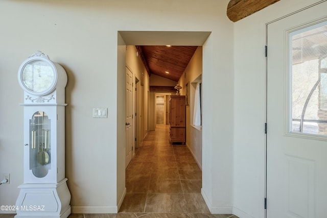 hallway featuring a wealth of natural light, light tile patterned floors, wooden ceiling, and vaulted ceiling