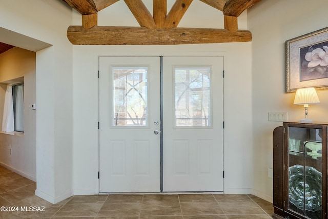 tiled entrance foyer featuring beamed ceiling