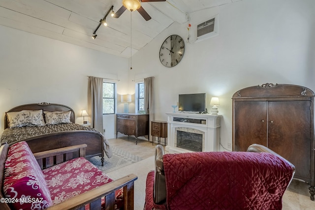 bedroom featuring track lighting, a wall mounted AC, ceiling fan, high vaulted ceiling, and a premium fireplace