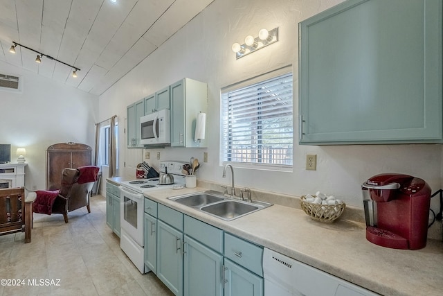 kitchen featuring rail lighting, white appliances, vaulted ceiling, sink, and light tile patterned floors