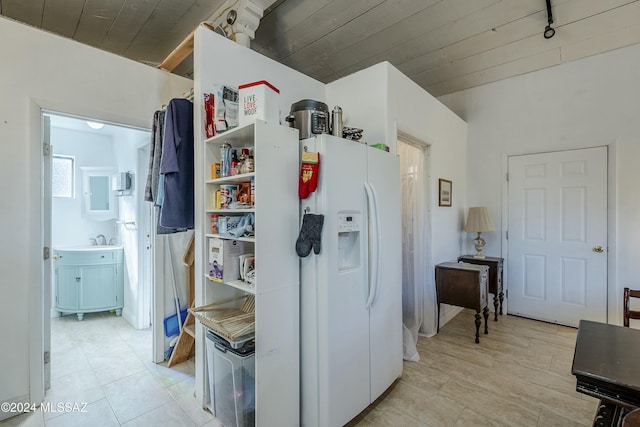 interior space featuring sink, rail lighting, wooden ceiling, white refrigerator with ice dispenser, and light tile patterned floors