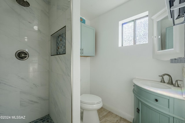 bathroom with tile patterned floors, toilet, vanity, and tiled shower