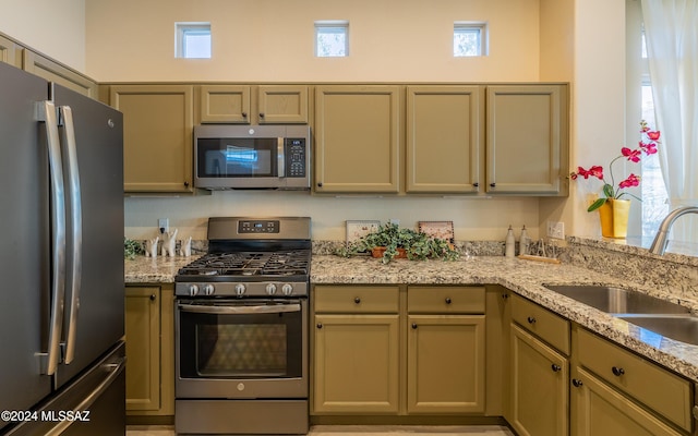 kitchen with light stone countertops, appliances with stainless steel finishes, and sink