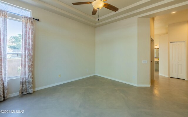 unfurnished room featuring a raised ceiling and ceiling fan