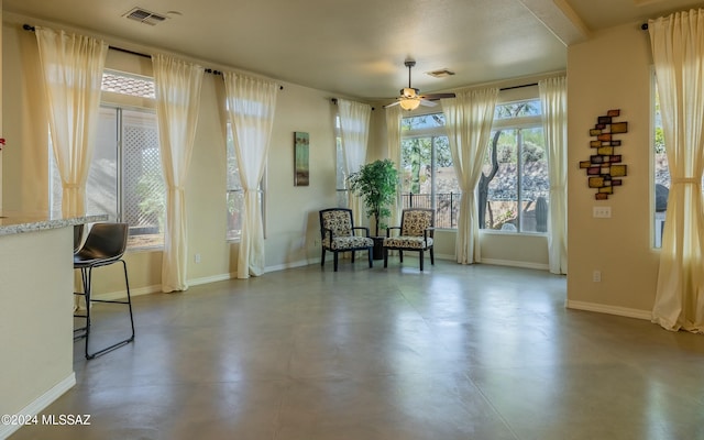 sitting room with ceiling fan and concrete floors