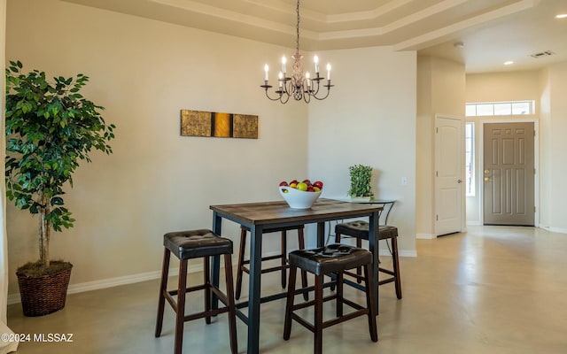 dining area featuring a chandelier, concrete floors, and a raised ceiling