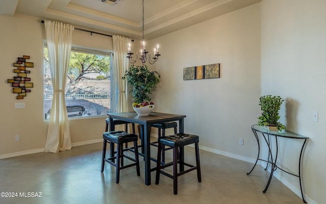 dining space featuring concrete floors, a tray ceiling, and a notable chandelier