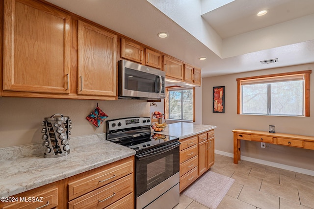 kitchen with light stone counters, light tile patterned floors, and stainless steel appliances