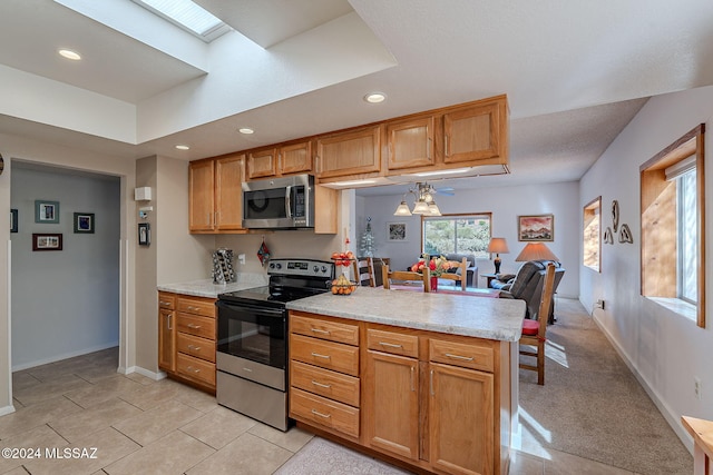 kitchen with light tile patterned flooring, light stone counters, a skylight, and appliances with stainless steel finishes