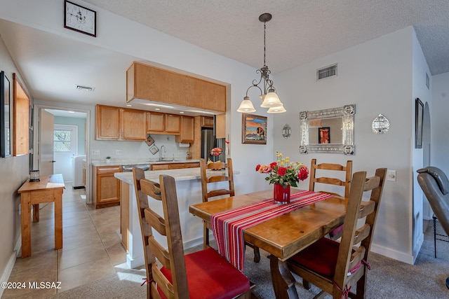 dining space with sink, a textured ceiling, and light tile patterned floors