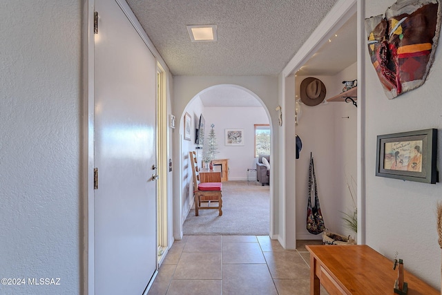 corridor with a textured ceiling and light tile patterned floors