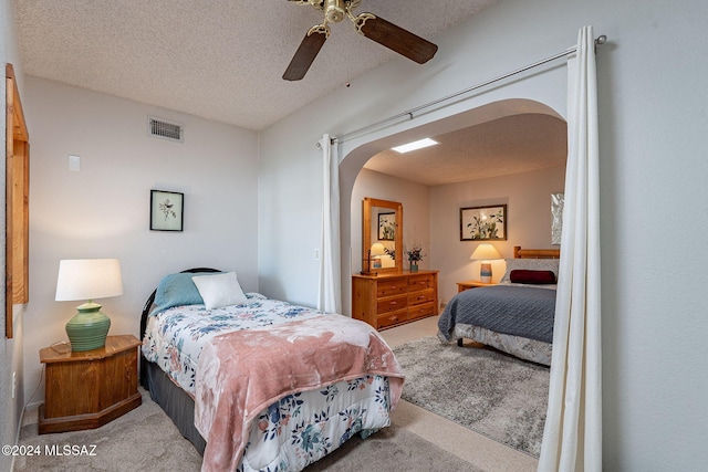 bedroom with a textured ceiling, light colored carpet, and ceiling fan