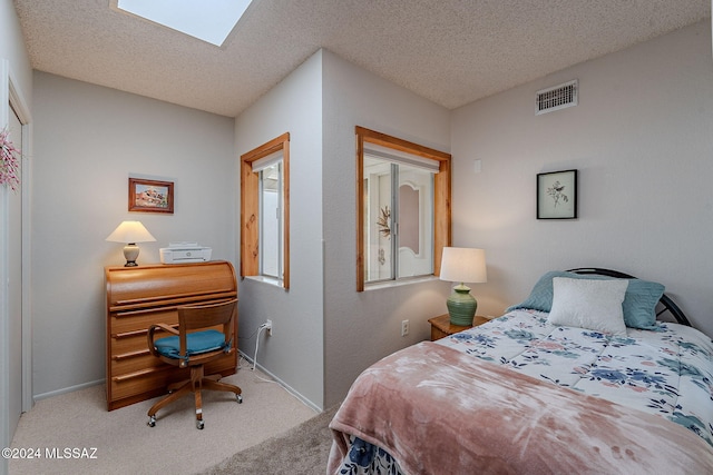 bedroom with light colored carpet, a textured ceiling, and a skylight