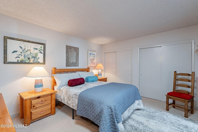 bedroom with multiple closets, a textured ceiling, and carpet