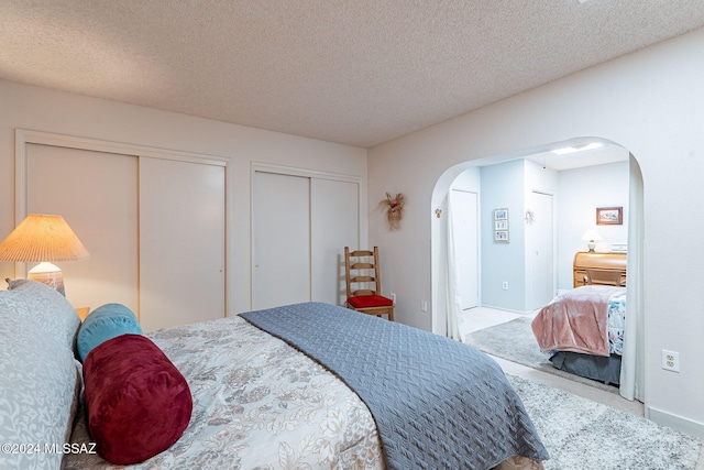 carpeted bedroom with multiple closets and a textured ceiling