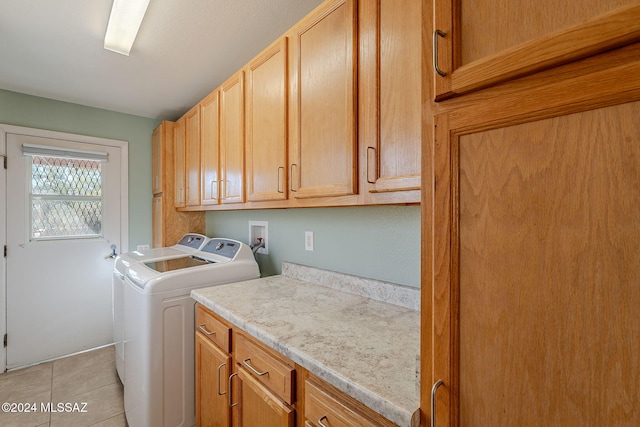 laundry room featuring cabinets, light tile patterned floors, and washing machine and clothes dryer