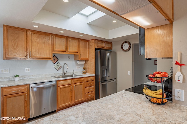 kitchen with sink, stainless steel appliances, a skylight, and a raised ceiling