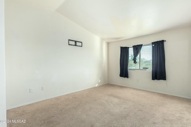 carpeted empty room featuring lofted ceiling