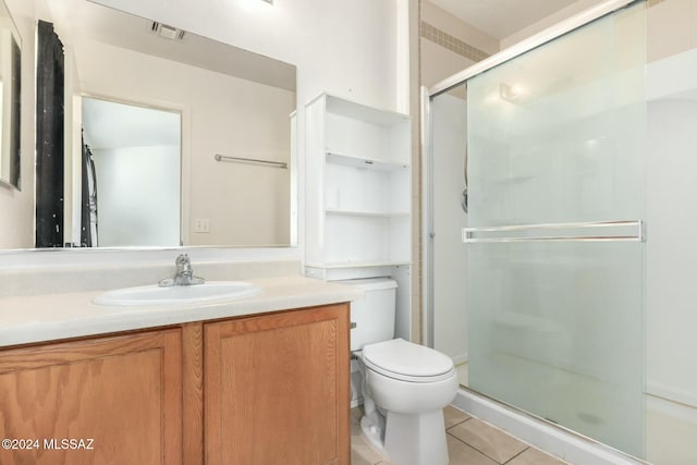 bathroom featuring tile patterned flooring, vanity, toilet, and a shower with door