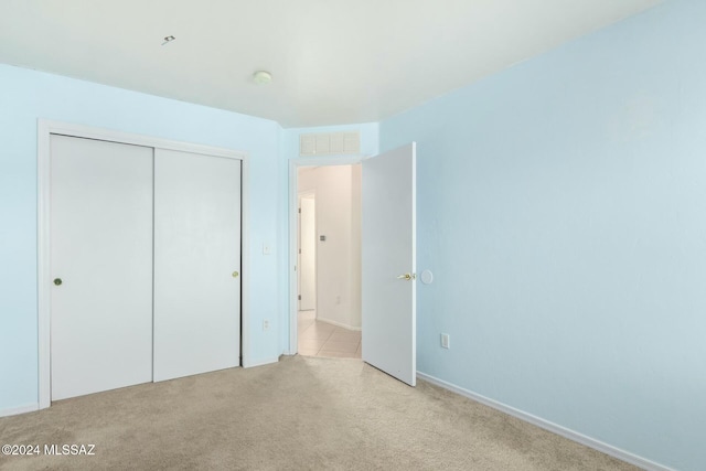 unfurnished bedroom with light carpet and a closet