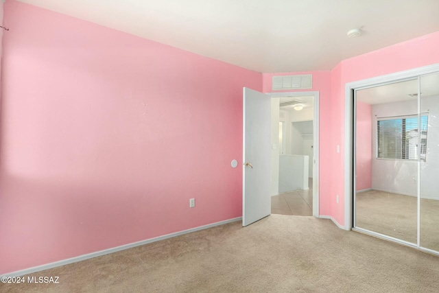 unfurnished bedroom with light carpet and a closet