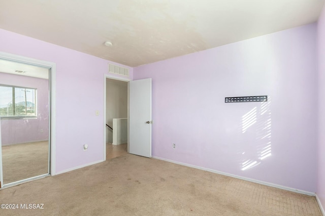 unfurnished bedroom featuring a closet and light colored carpet