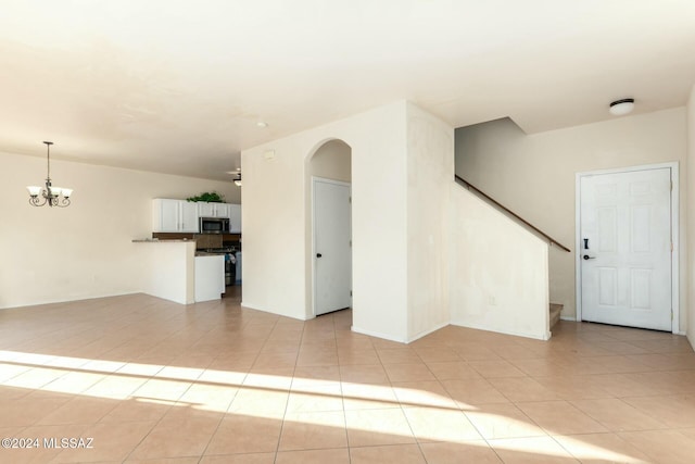 unfurnished living room with light tile patterned floors and an inviting chandelier