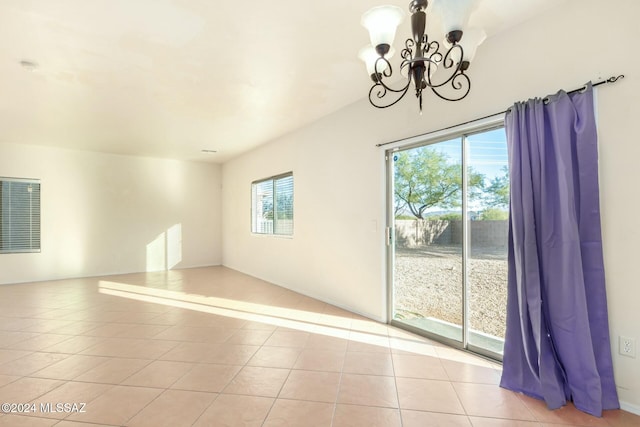 tiled spare room featuring a chandelier